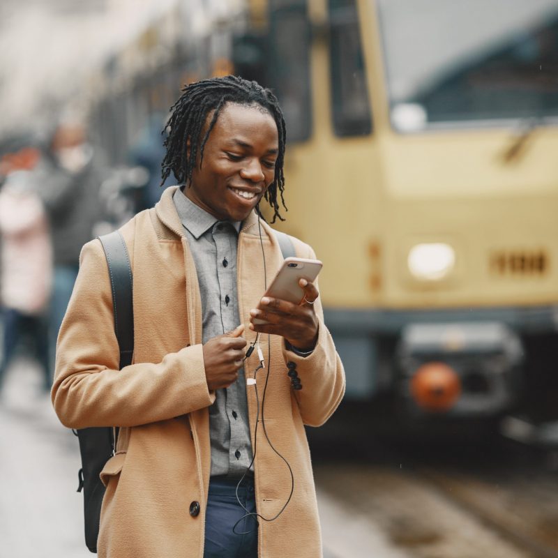 Man by the bus. Guy with mobile phone.